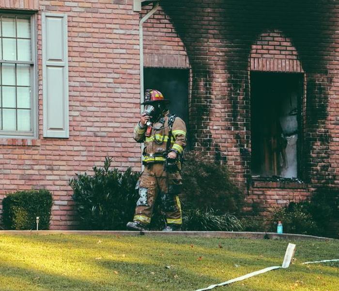 Fire fighter coming out of fire damaged house
